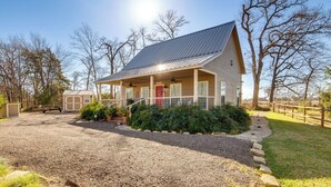 A single-story house with a porch, a red door, and a gravel driveway. - Anglers' Haven! Cedar Creek Reservoir Getaway (Tool)