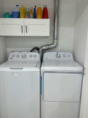 Ein Waschraum mit zwei weißen Waschmaschinen und einem darüberliegenden Schrank für Reinigungsmittel.