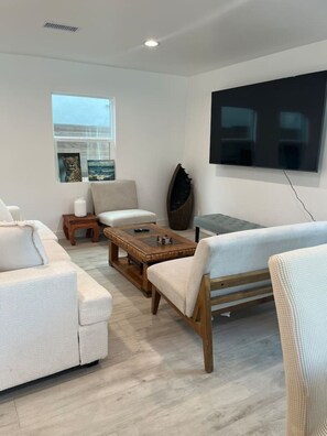 A modern living room with a sofa, armchairs, a coffee table, and a TV mounted on the wall. - Brand-New Home. Great Location. Monthly Discounts (Los Angeles)