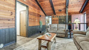 A wooden interior with a sofa, a wooden coffee table, and a rug.