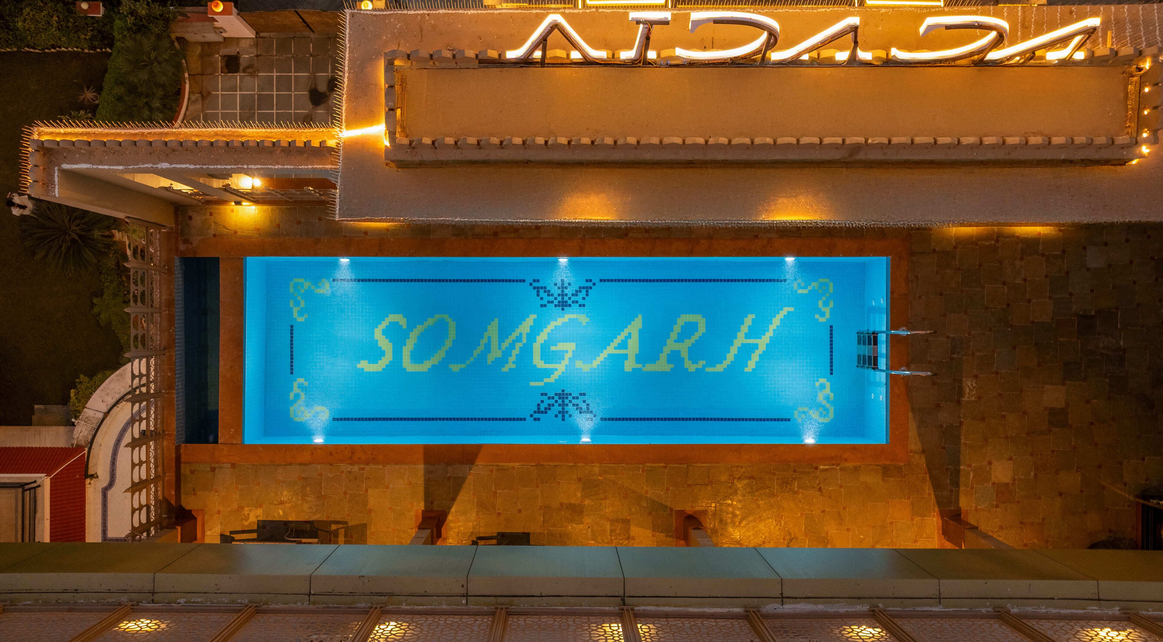 A pool area with a sign reading "SOMGARH" and a tiled wall.