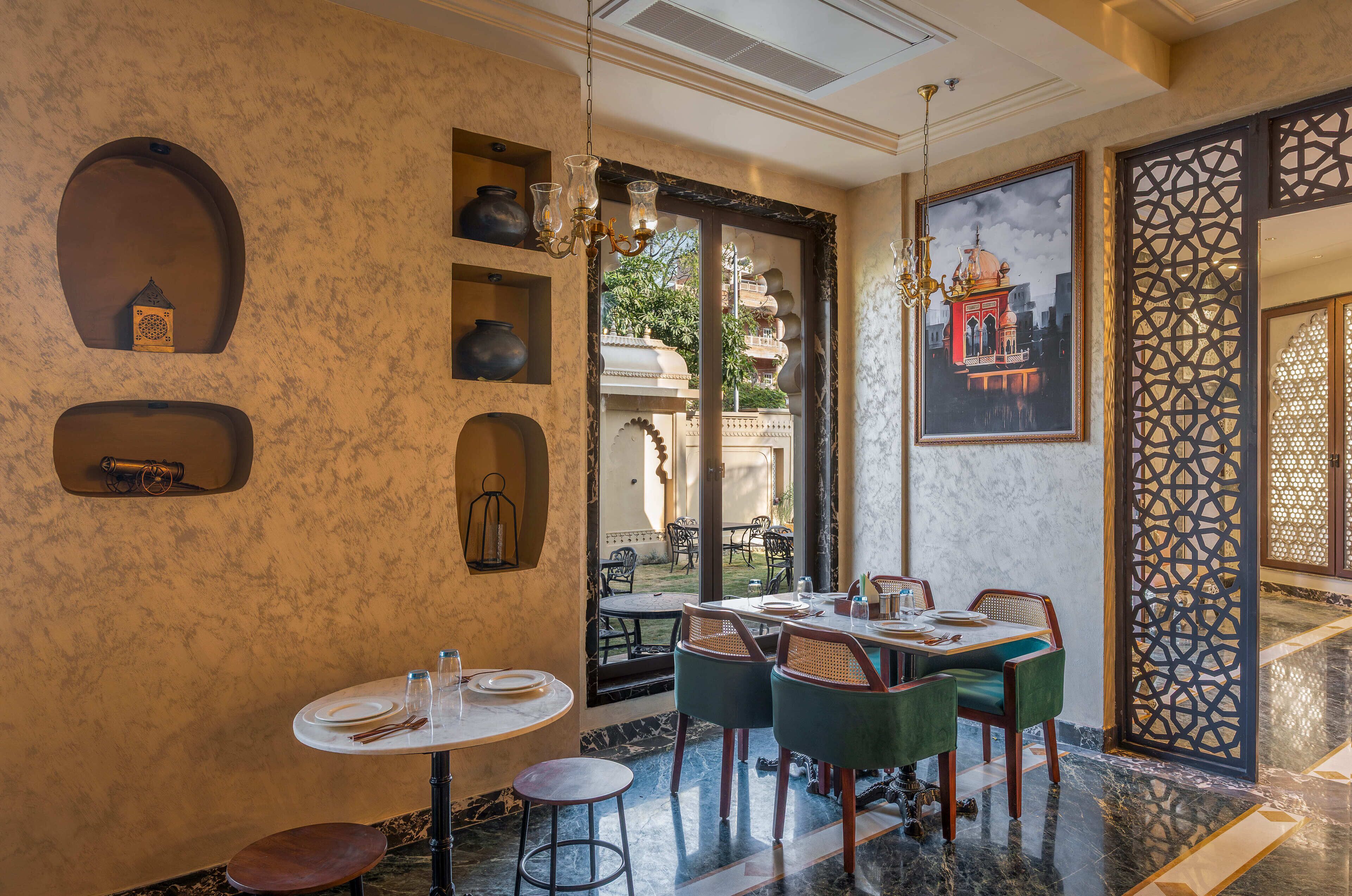 A restaurant with a marble floor, green upholstered chairs, and a large decorative screen.