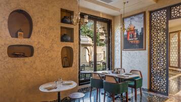 A restaurant with a marble floor, green upholstered chairs, and a large decorative screen.