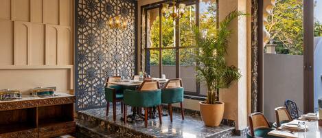 A dining area with a marble floor, a patterned wall, and a large window with a view of trees.