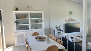 A dining area with a white table, chairs, and a cabinet with glass doors. - Life's A Beach with views to Green Island (Manyana)
