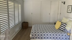 A bedroom with a bed, a wardrobe, a radiator, and a wall-mounted light fixture.