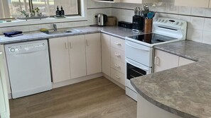Une cuisine moderne équipée d’un lave-vaisselle, d’une cuisinière et d’un plan de travail agrémenté d’ustensiles de cuisine.
