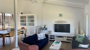 A living room with a dark blue sofa, a white coffee table, and a TV mounted on the wall.