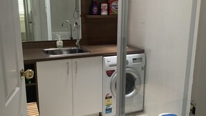 Una cuina petita amb un rentaplat, una rentadora i un mirall sobre el rentaplat.