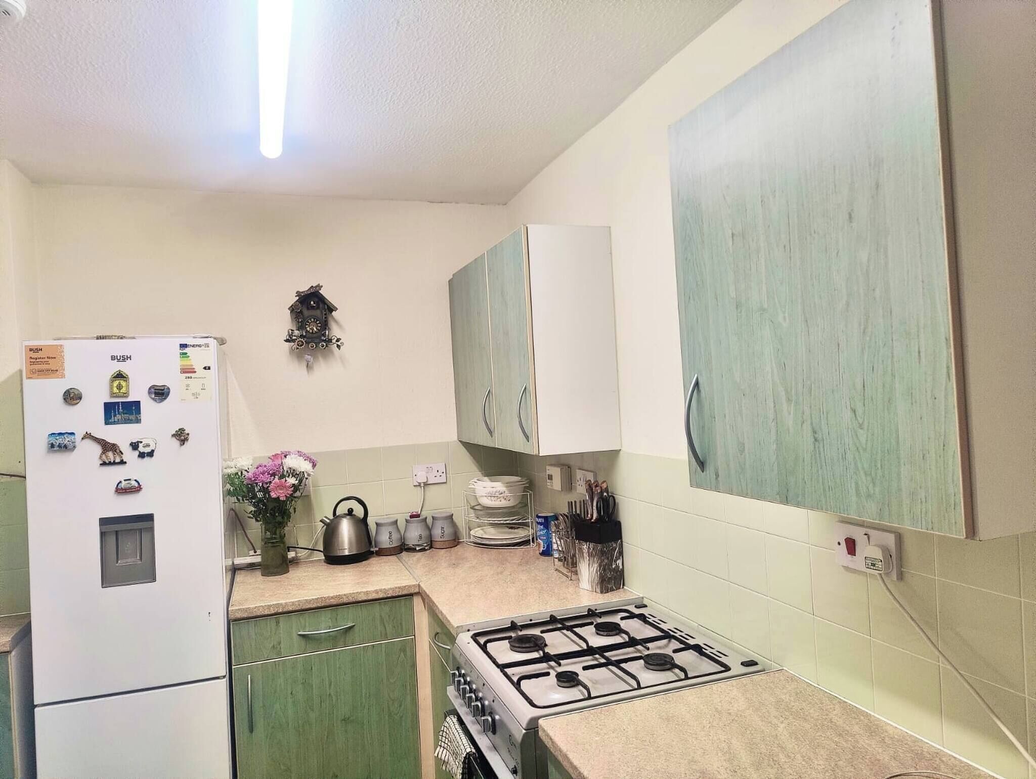 A kitchen with a refrigerator, stove, and cabinets.