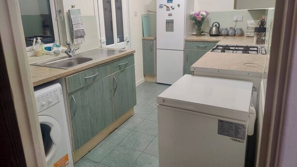 Una cucina compatta con lavatrice, frigorifero e fornello.