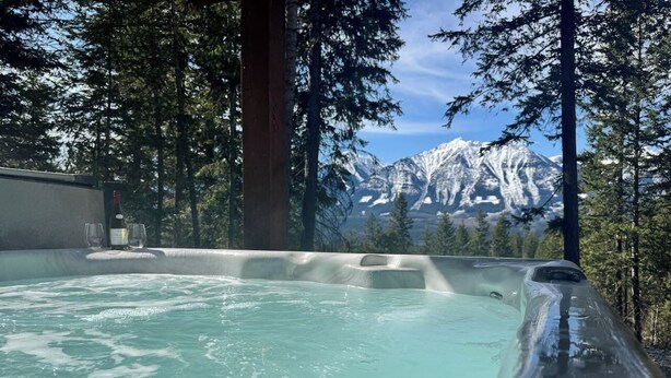 Ein Whirlpool mit Blick auf die Berge, umgeben von Bäumen.