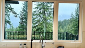 Eine Küche mit einem großen Fenster mit Blick auf einen Wald und Berge.