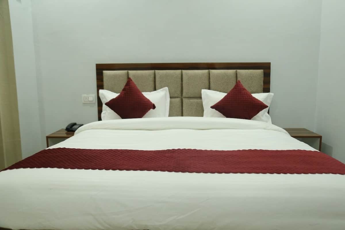 A neatly made bed with a white and red bedspread, two red pillows, and a wooden headboard.