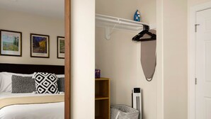 Habitación de hotel con cama, espejo, calefactor en la pared y repisa con un platero azul.