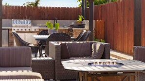 Un patio al aire libre con una parrilla, una zona de estar y un hogar.