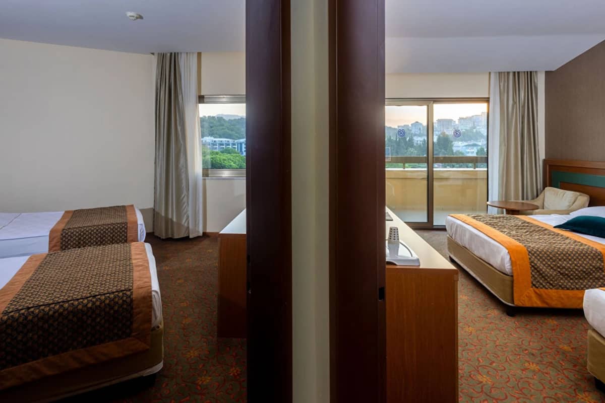 A hotel room with two beds, a desk, and a view of the city.