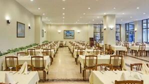 Un amplio comedor con varias mesas y sillas, dispuestas en filas.