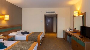 Una habitación de hotel con dos camas, un escritorio, un televisor y un espejo.