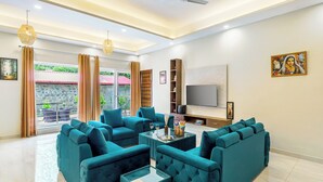 Ein modernes Wohnzimmer mit Türkis-farbenen Sofas, einem Glastisch und einem Flachbildfernseher.