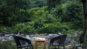 Ein Tisch mit zwei Stühlen vor einer grünen Flusslandschaft.