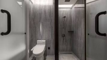 A modern bathroom with a glass partition, a toilet, and a shower area.