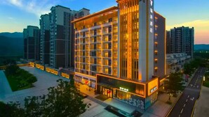A multi-story hotel with a modern design, featuring a prominent entrance and a well-lit facade. - RAY TOUR (Zhaoqing)