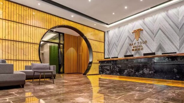 A hotel reception area with a marble floor, a reception desk, and a seating area with sofas. - RAY TOUR (Zhaoqing)