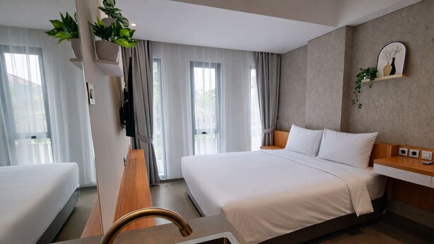 Habitación de hotel con una cama grande, un escritorio de madera, un lavamanos integrado y vistas al exterior a través de amplias ventanas.
