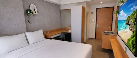 A hotel room with a bed, a desk, and a bathroom.