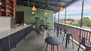 Un área de estar moderna al aire libre con bar, plantas colgantes y vistas de la ciudad.