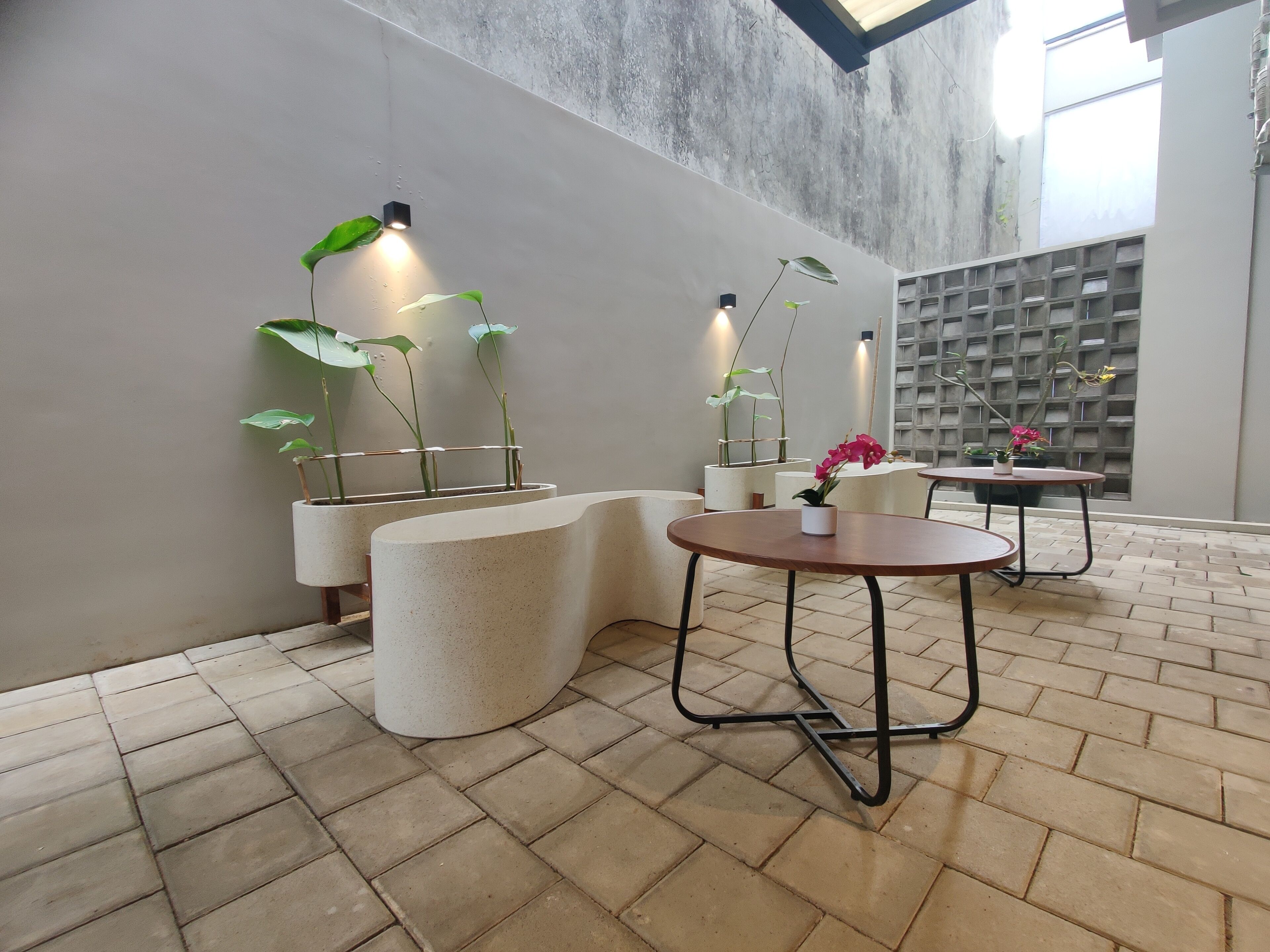 A modern interior with a curved seating area, potted plants, and a brick floor.