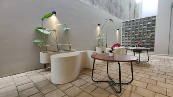 A modern interior with a curved seating area, potted plants, and a brick floor.