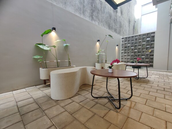 A modern interior with a curved seating area, potted plants, and a brick floor. - The Orchid by FLAT06 (Jakarta)
