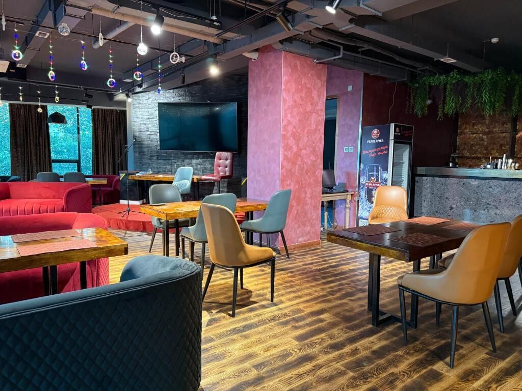 Un café moderno con suelo de madera, asientos rojos y azules, y una zona de bar.