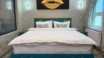 A bedroom with a bed, a large wall art of lips, and a window.