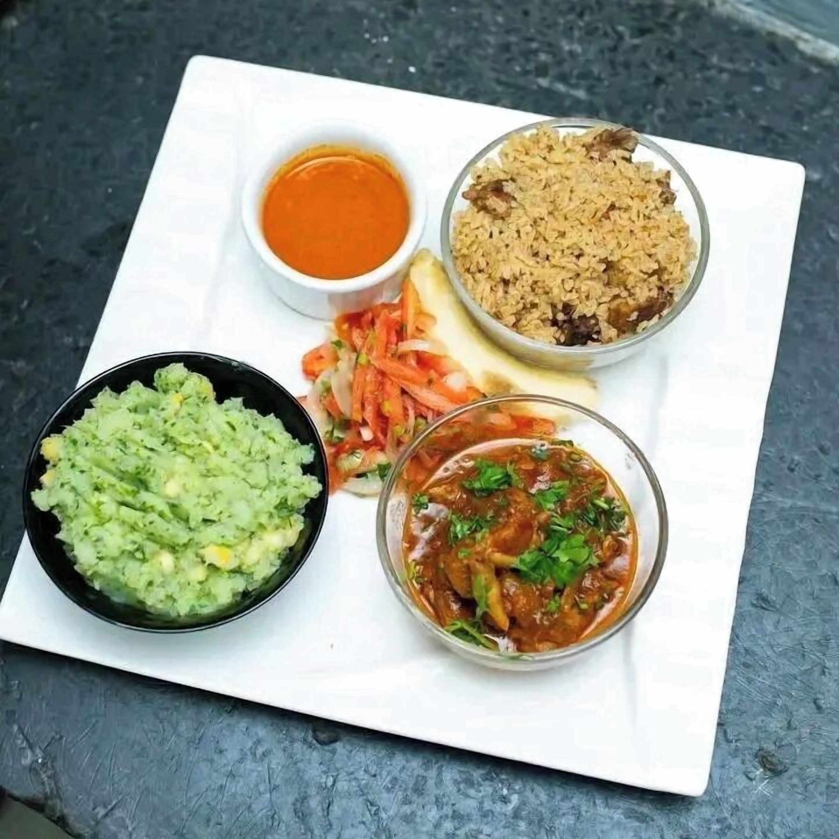 A white plate with various food items including a bowl of guacamole, a bowl of salsa, a bowl of rice, a bowl of curry, and a small bowl of sauce.