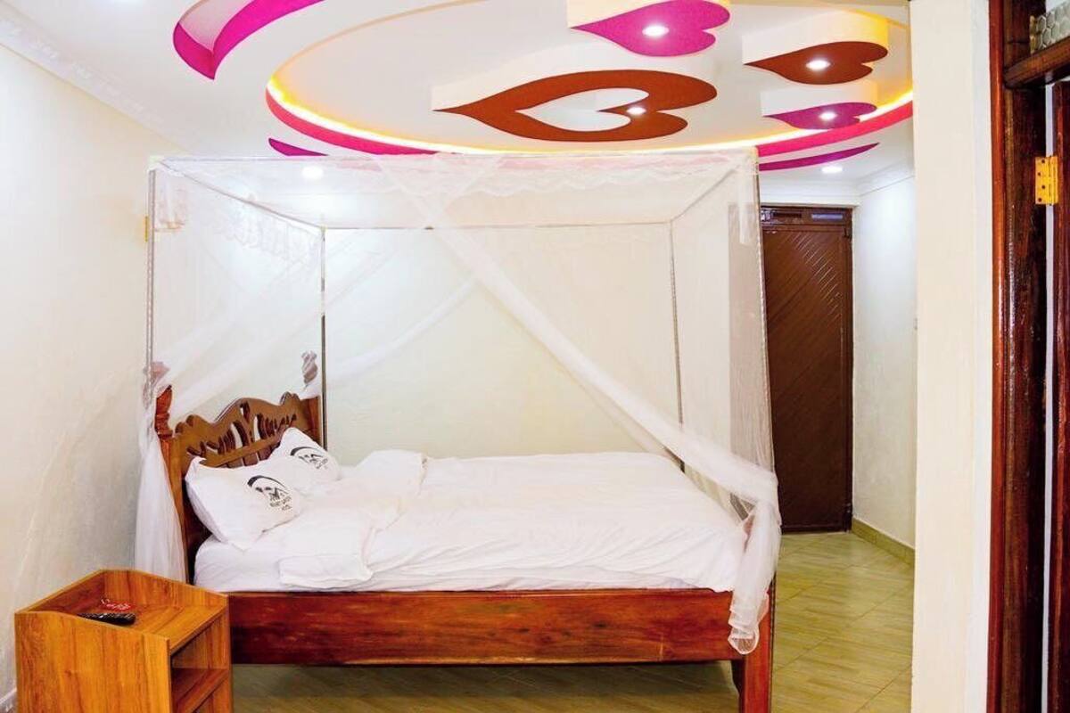 A single bed with a wooden frame and white bedding, a wooden nightstand, and a ceiling with a circular light fixture.