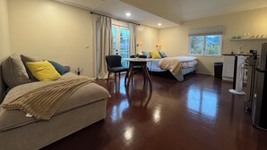 Habitación de hotel compacta con dos camas, una mesa de comedor, una pequeña cocina y una ventana con vistas al exterior.