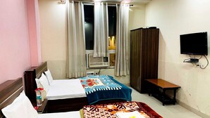 A hotel room with two beds, a TV, a window with curtains, and a wooden wardrobe. - Shri Kamal Dham Hotel Vrindavan (Vrindavan)