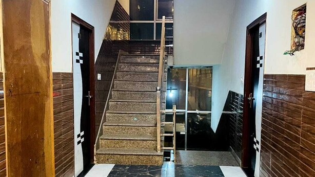 A hallway with a marble floor, a staircase, and wooden doors. - Shri Kamal Dham Hotel Vrindavan (Vrindavan)