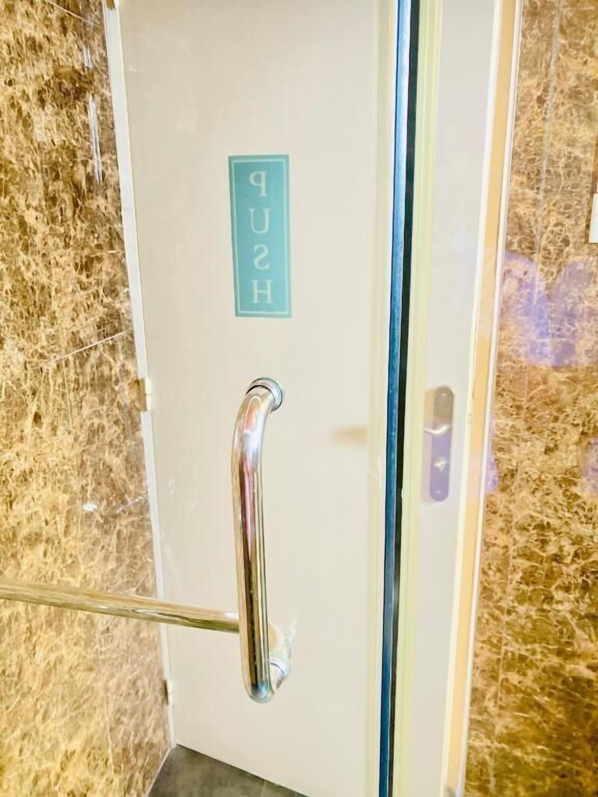 Una puerta con manija metálica y un cartel encima.