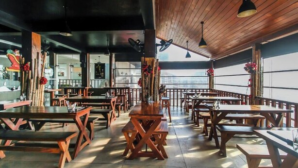 A restaurant with wooden tables and benches, a high ceiling, and large windows. - Hotel 198 Negombo (Negombo)
