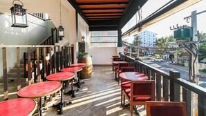 A balcony with red tables and chairs, a wooden ceiling, and a view of the street. - Hotel 198 Negombo (Negombo)