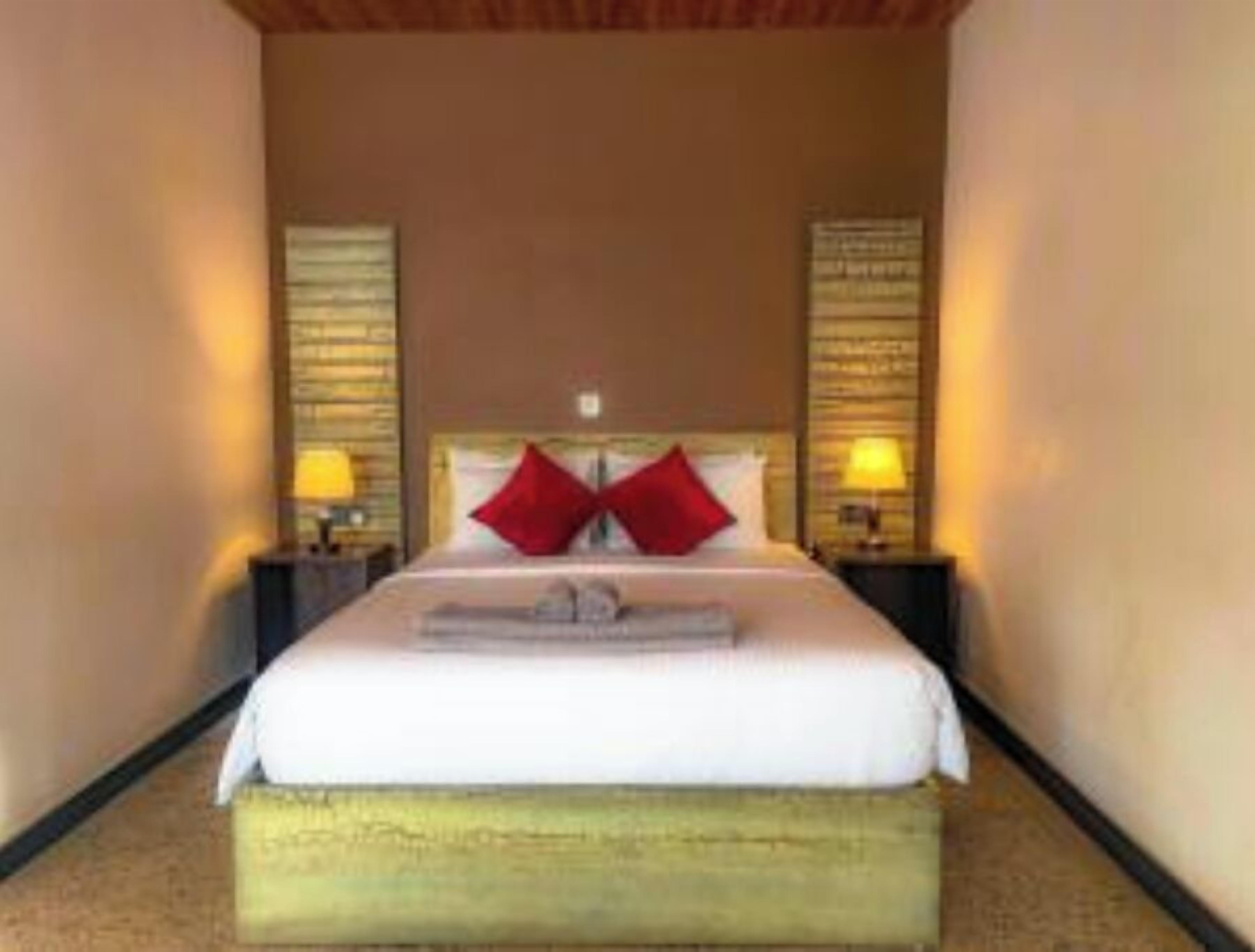 A hotel room with a bed, two nightstands, and a wall-mounted lamp.