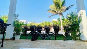 A covered outdoor area with a table, a bicycle, and potted plants. - CDM Villas (Kiwengwa)