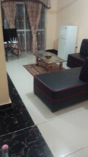 A living room with a sofa, a coffee table, a TV, and a dining area with chairs and a table. - Furnished Flat Apartment Bamburi Beach Mombasa (Mombasa)