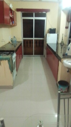 A kitchen with a refrigerator, stove, and cabinets. - Furnished Flat Apartment Bamburi Beach Mombasa (Mombasa)