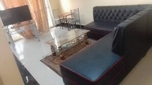 A living room with a sofa, a coffee table, and a TV. - Furnished Flat Apartment Bamburi Beach Mombasa (Mombasa)