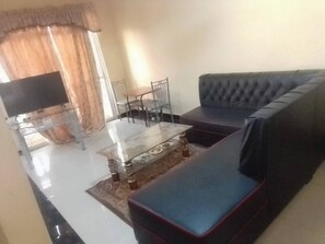 A living room with a sofa, a coffee table, and a TV. - Furnished Flat Apartment Bamburi Beach Mombasa (Mombasa)